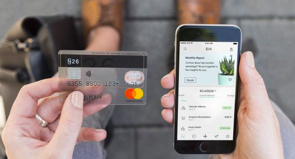 personne tenant une carte de credit N26 et son smartphone